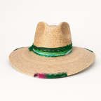 Front eye-level view of the natural straw fedora displayed on a stand with green and pink decorative accents.