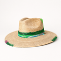 Front three-quarter view of a natural straw fedora with a wide brim, green braided crown band, and pink trim.