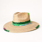 Front three-quarter view of a natural straw fedora with a wide brim, green braided crown band, and pink trim.