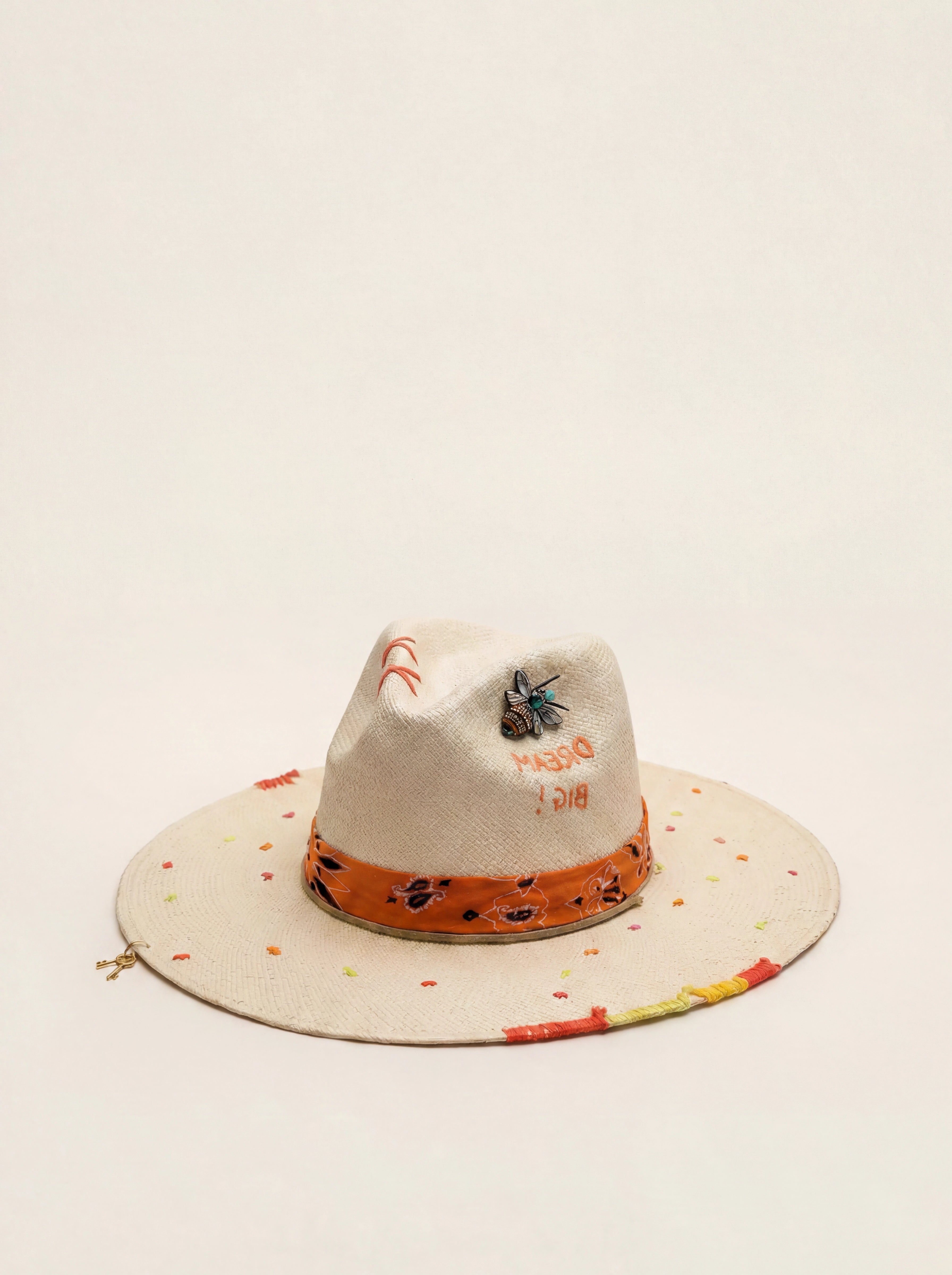 White cowboy hat with colorful brim on a light beige background